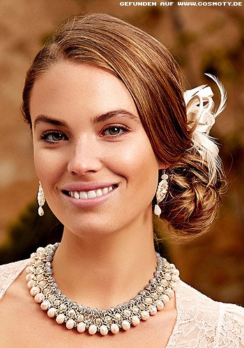 Seitlich gesteckter Chignon mit Blüten- und Federschmuck