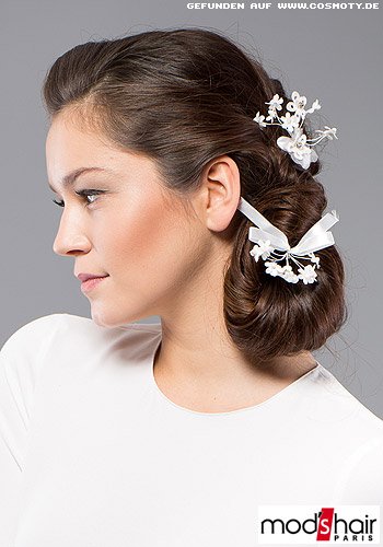 Seitlich gesteckter länglicher Chignon mit zarten weißen Blüten