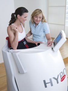 Eine Frau trainiert mit einem Hypoxi Gerät im Sitzen