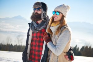 Pärchen läuft im Schnee mit Sonnenbrillen