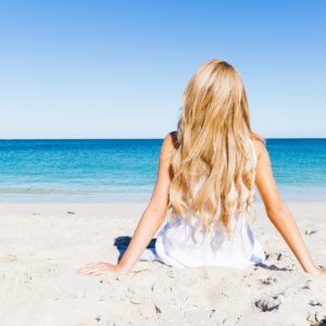 Junge Frau sitzt am Strand