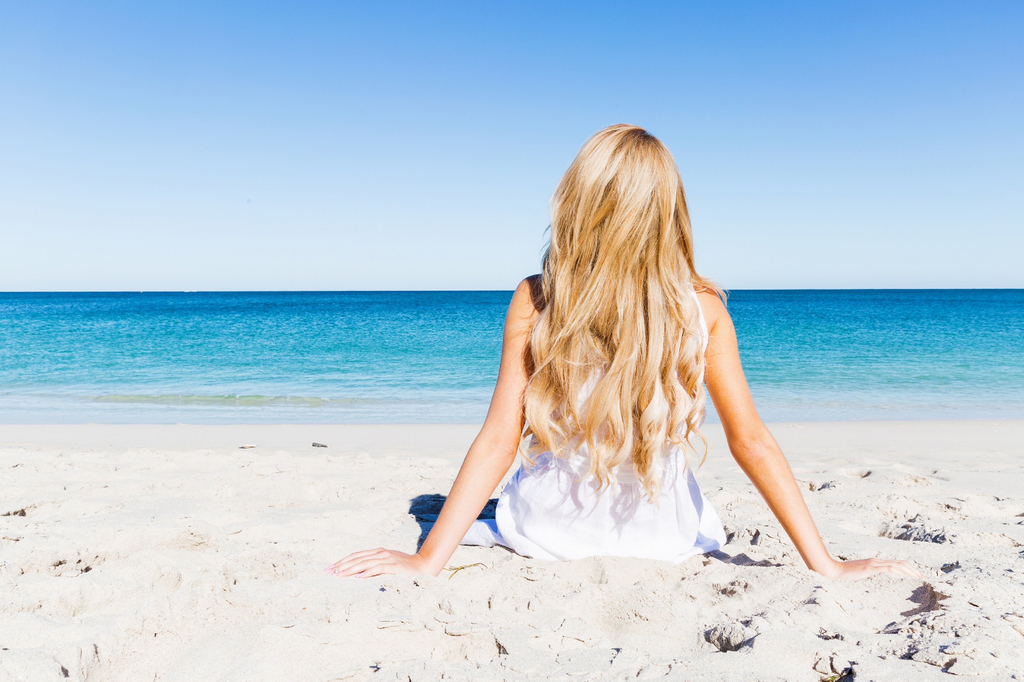 Junge Frau sitzt am Strand