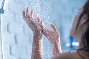 frau in dusche hält hände unter wasser