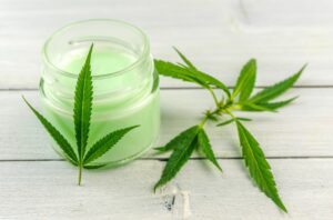 cbd-creme in döschen dekoriert mit hanfblättern