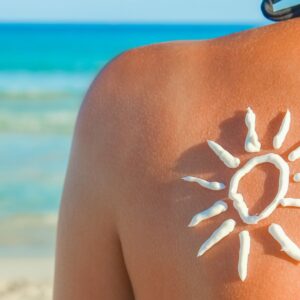 frau am strand mit sonnencreme auf dem ruecken