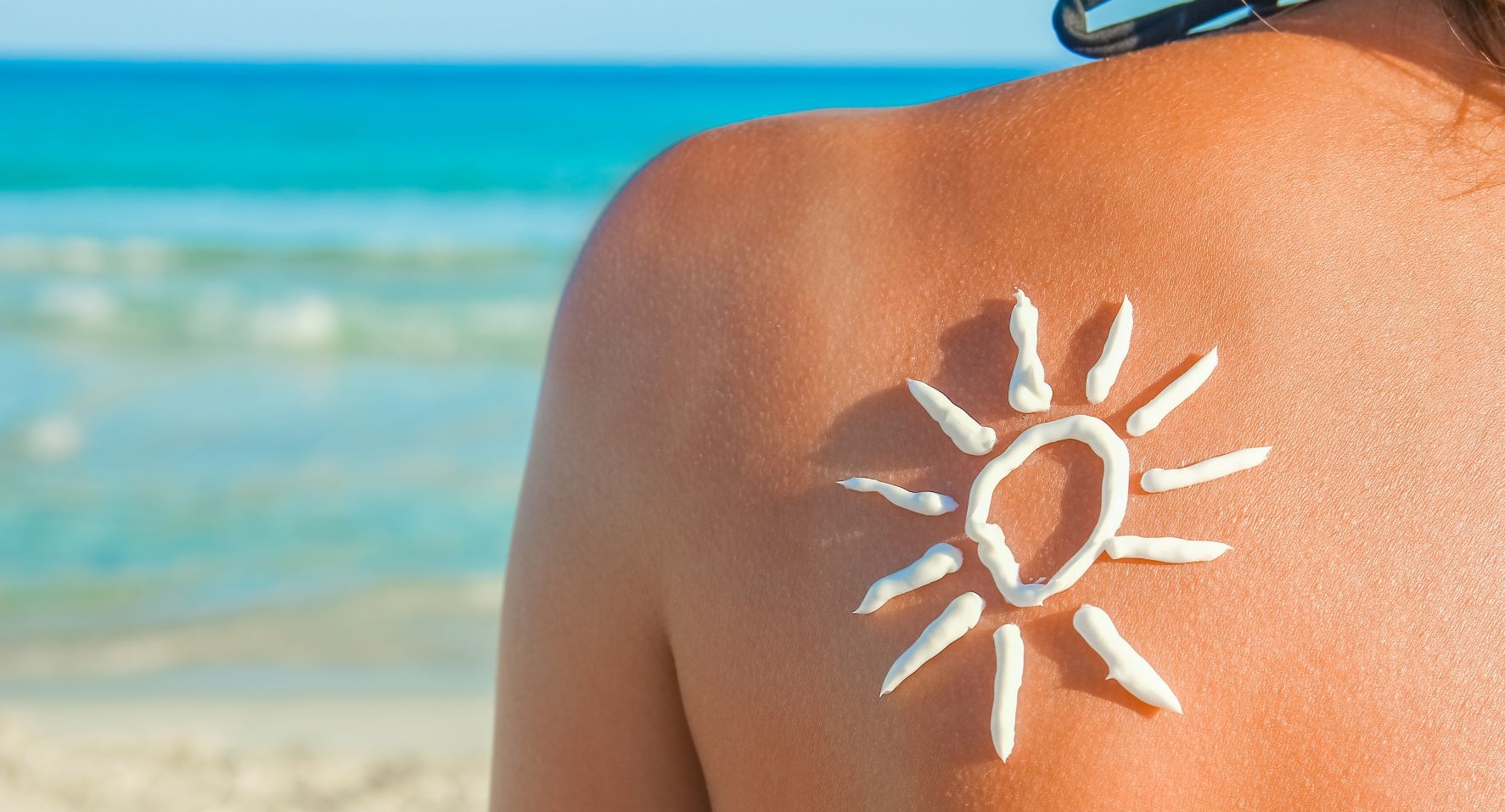 frau am strand mit sonnencreme auf dem ruecken