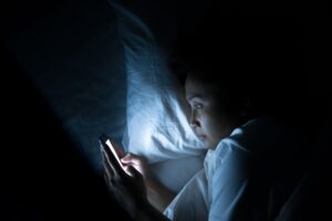 asiatische frau im bett mit handy in der hand