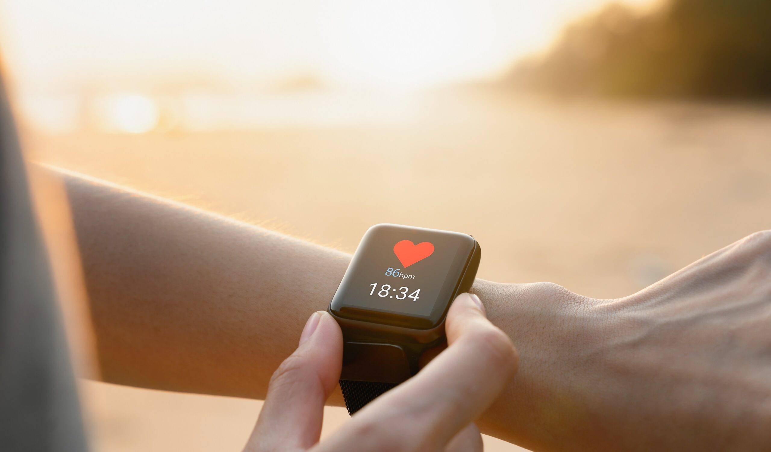 smartwatch an handgelenk vor strandkulisse