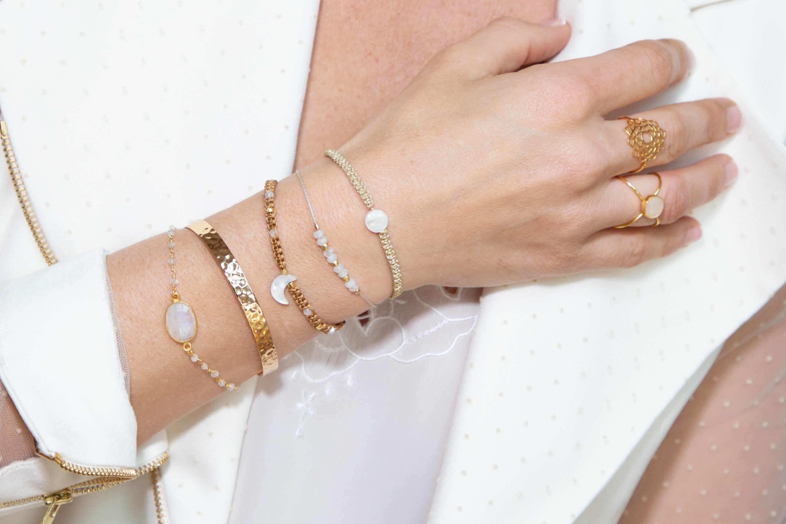Hand und Unterarm mit einigen Ringen und Armändern in Gold und mit Edelsteinen zu sehen.