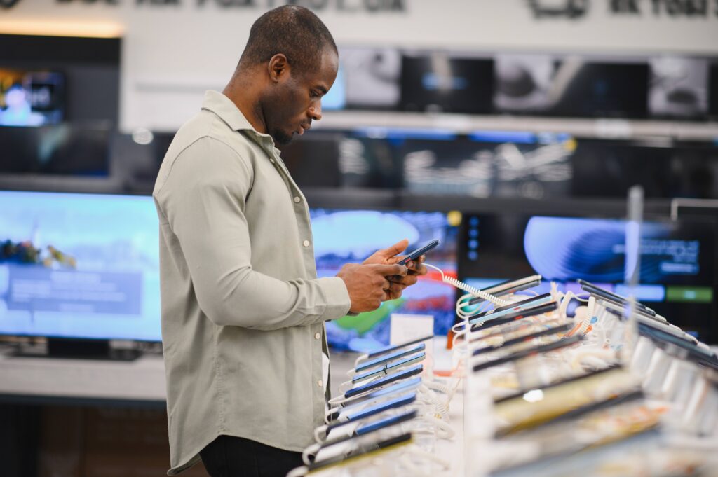 Mann vergleicht Smartphones im Elektrofachhandel.