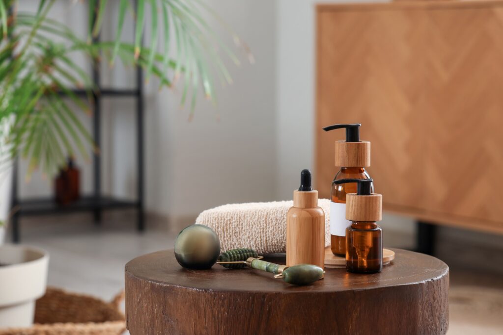 Auf einem Holztisch in einem Badezimmer sind verschiedene Pflegeprodukte, ein Gesichtsroller und ein Handtuch aufgestellt.