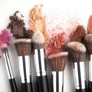 Verschiedene Make-Up-Pinsel mit Produktresten an den Borsten vor einem weißen Untergrund.