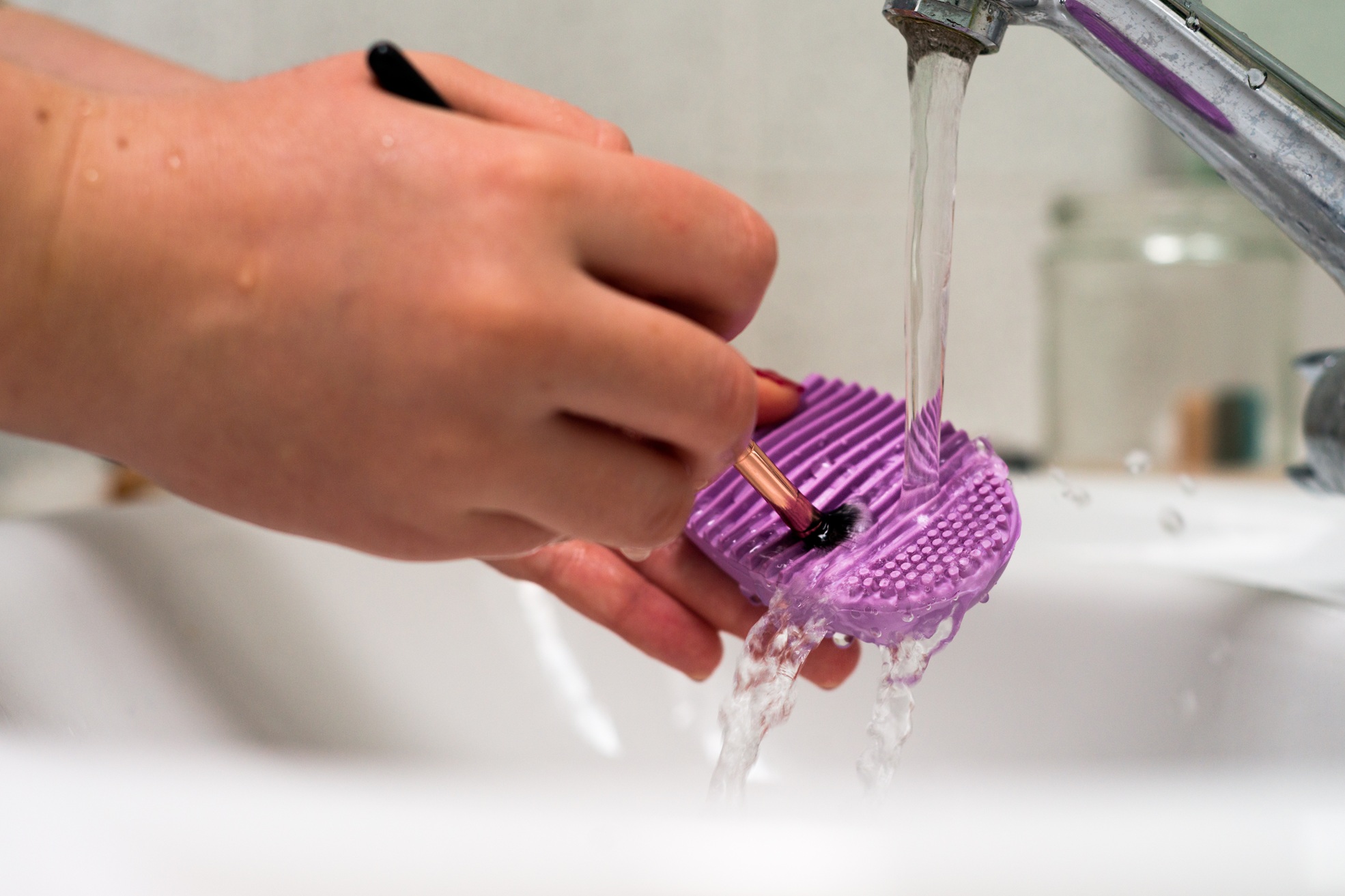 Make-Up-Pinsel wird unter fließendem Wasser ausgewaschen.