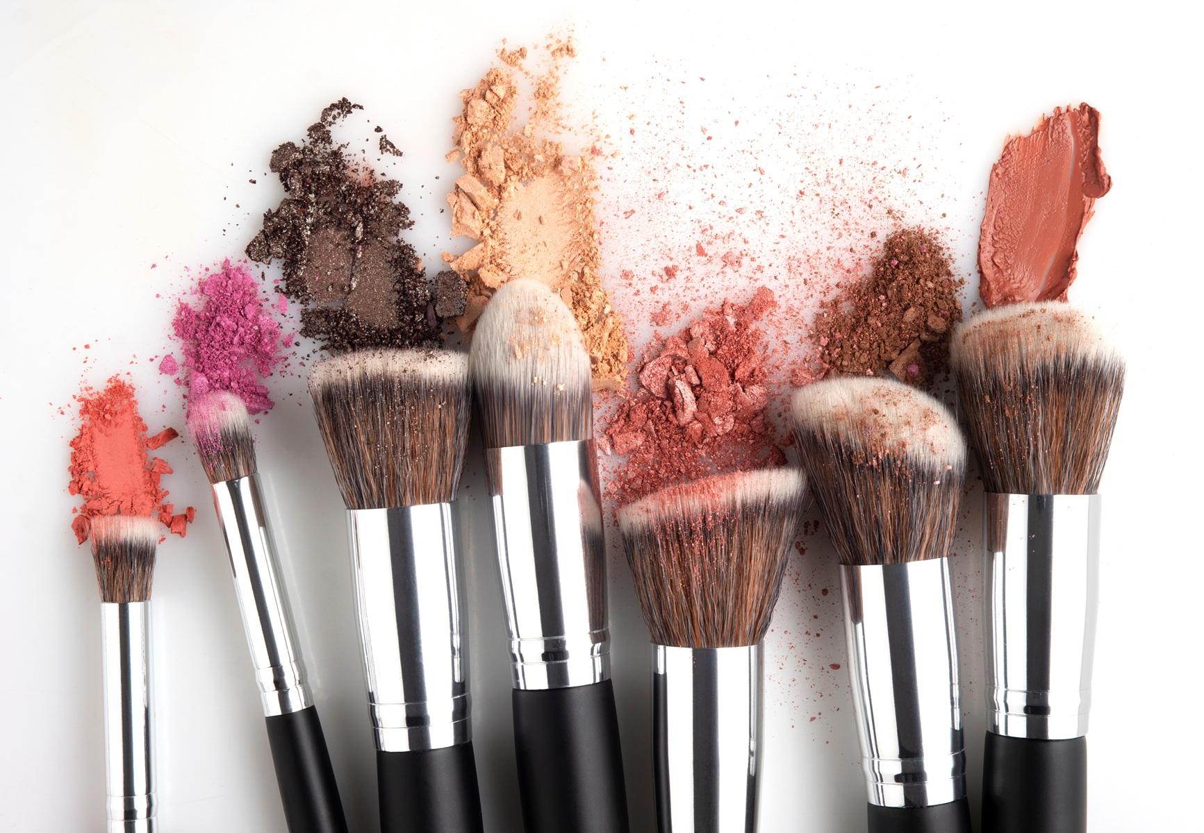 Verschiedene Make-Up-Pinsel mit Produktresten an den Borsten vor einem weißen Untergrund.