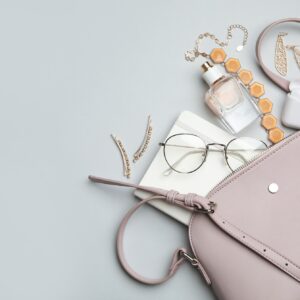 Handtasche in Lederoptik liegt offen auf glatter Oberfläche und der Inhalt quillt heraus.