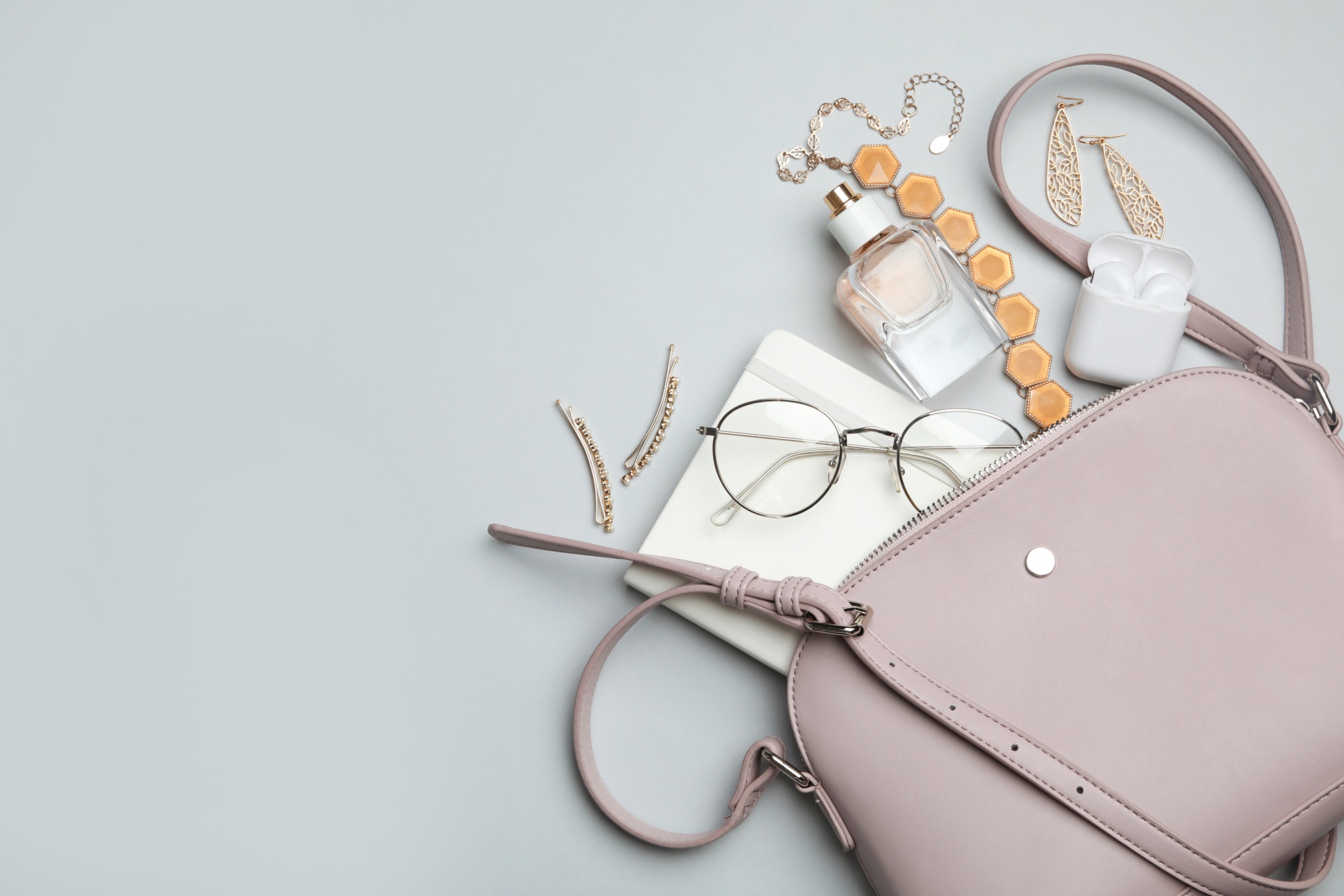 Handtasche in Lederoptik liegt offen auf glatter Oberfläche und der Inhalt quillt heraus.