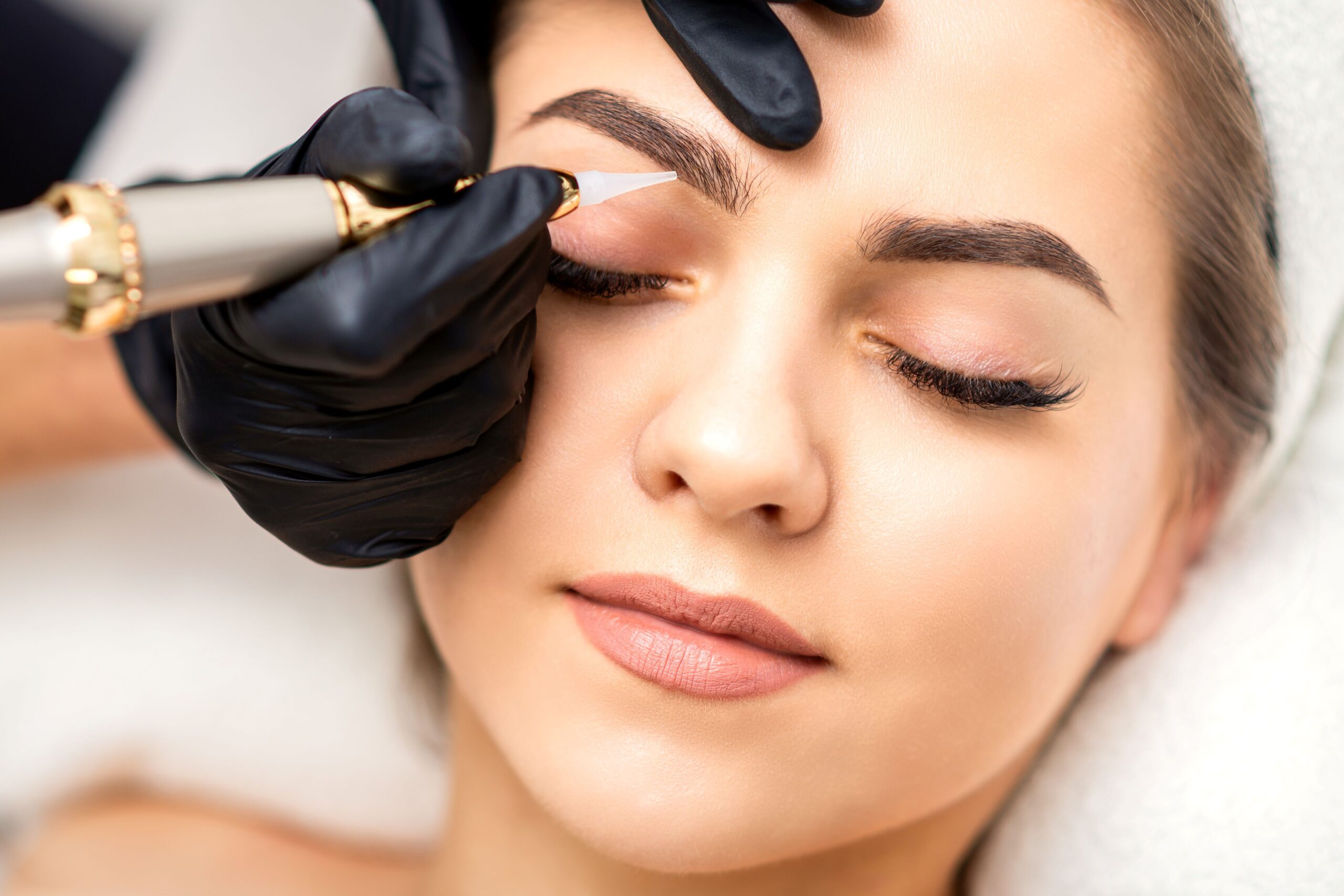 Die Augenbrauen einer Frau werden mit einem Permanent Make-Up optisch verdichtet.