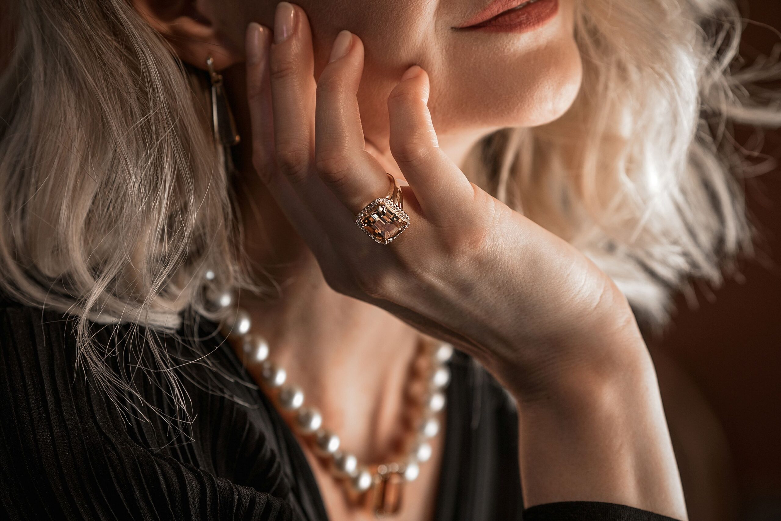 Eine Dame trägt einen hochwertigen Diamantring und eine Perlenkette.