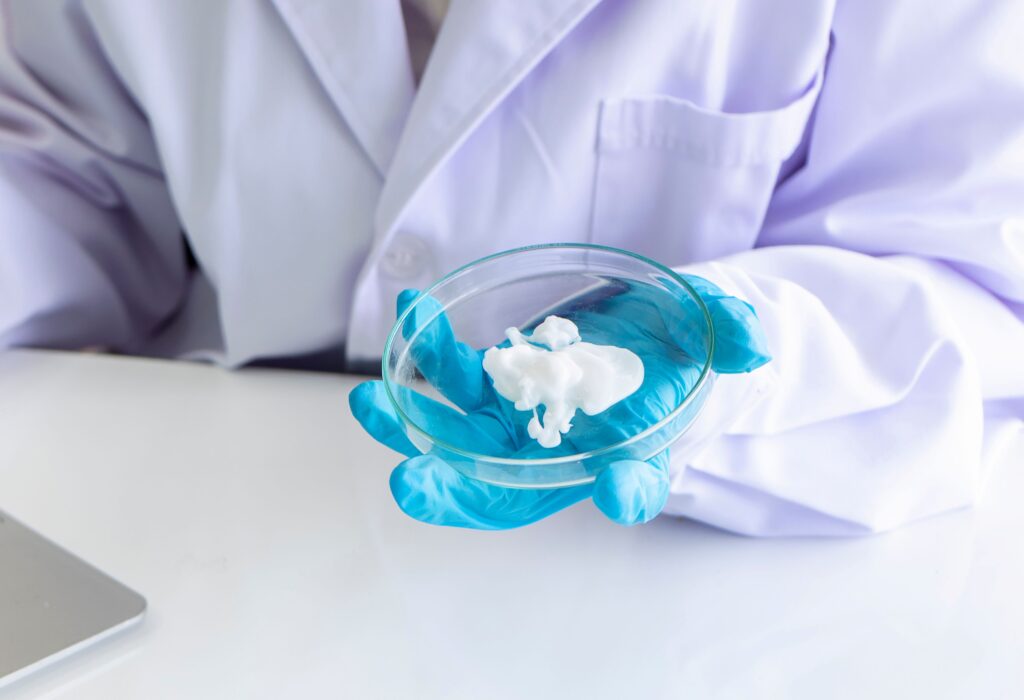 Eine Wissenschaftlerin hält eine Probe einer zu analysierenden Creme in der Hand.