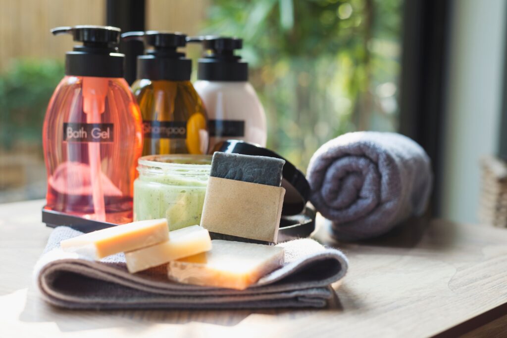 Einige Flaschen mit Shampoo, Badegel und Körperlotion sowie Seife und Handtücher wurden auf einem Holztisch platziert.
