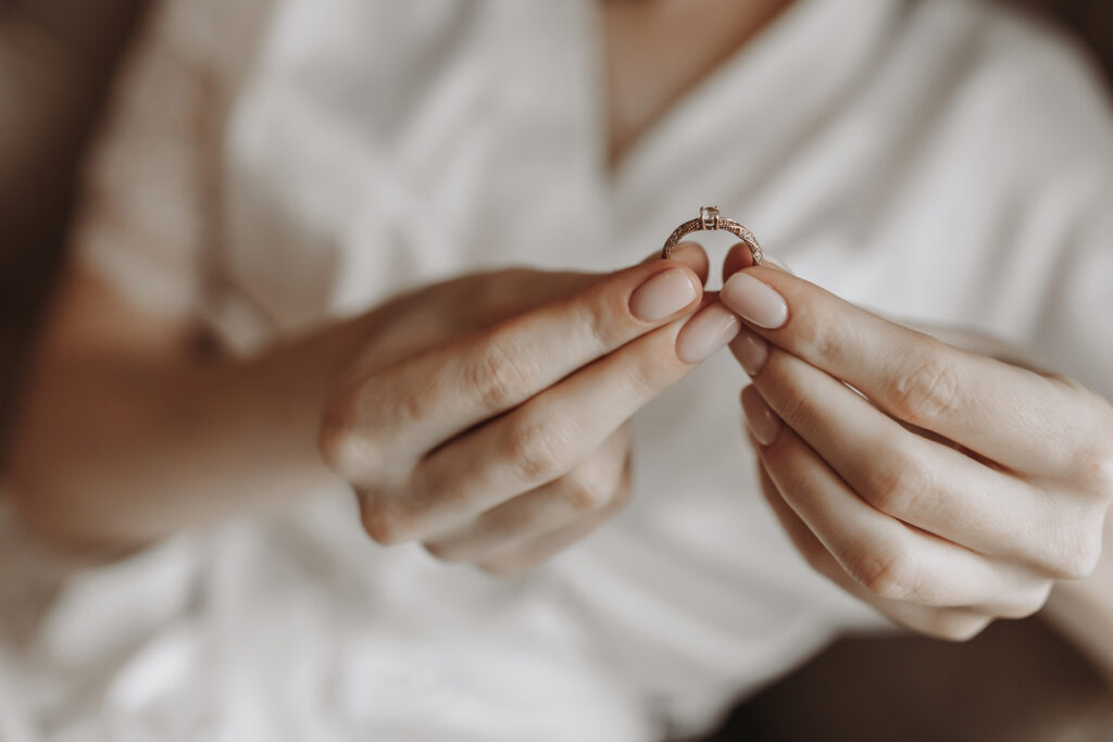 Eine Frau hält einen Ring mit einem dezenten Stein in der Hand.