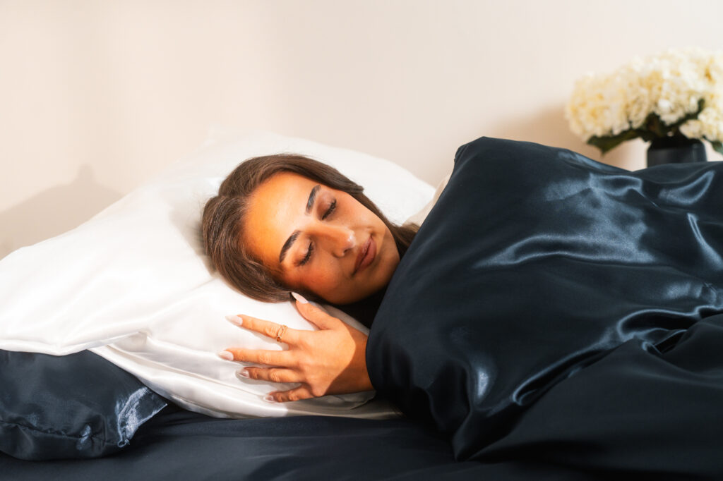 Eine Frau liegt schlafend im Bett und hält ihr Kopfkissen fest.
