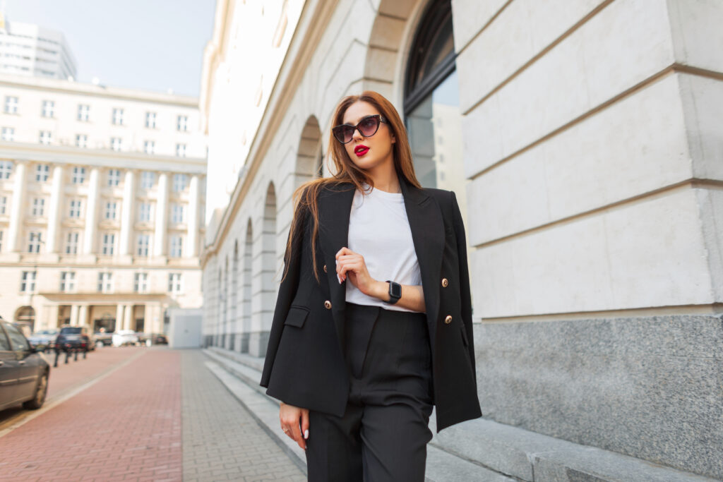 Eine moderne Frau in einem eleganten schwarzen Freizeitanzug und Vintage-Sonnenbrille schlendert durch die Stadt