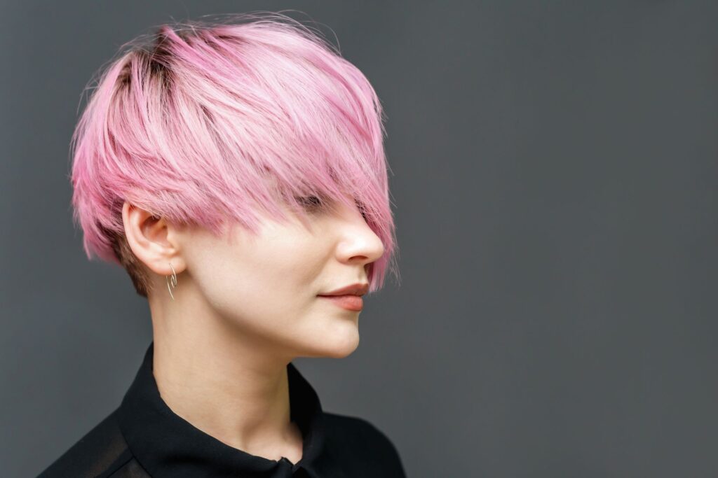 Frau mit kurzen rosafarbenen Haaren vor einem grauen Hintergrund