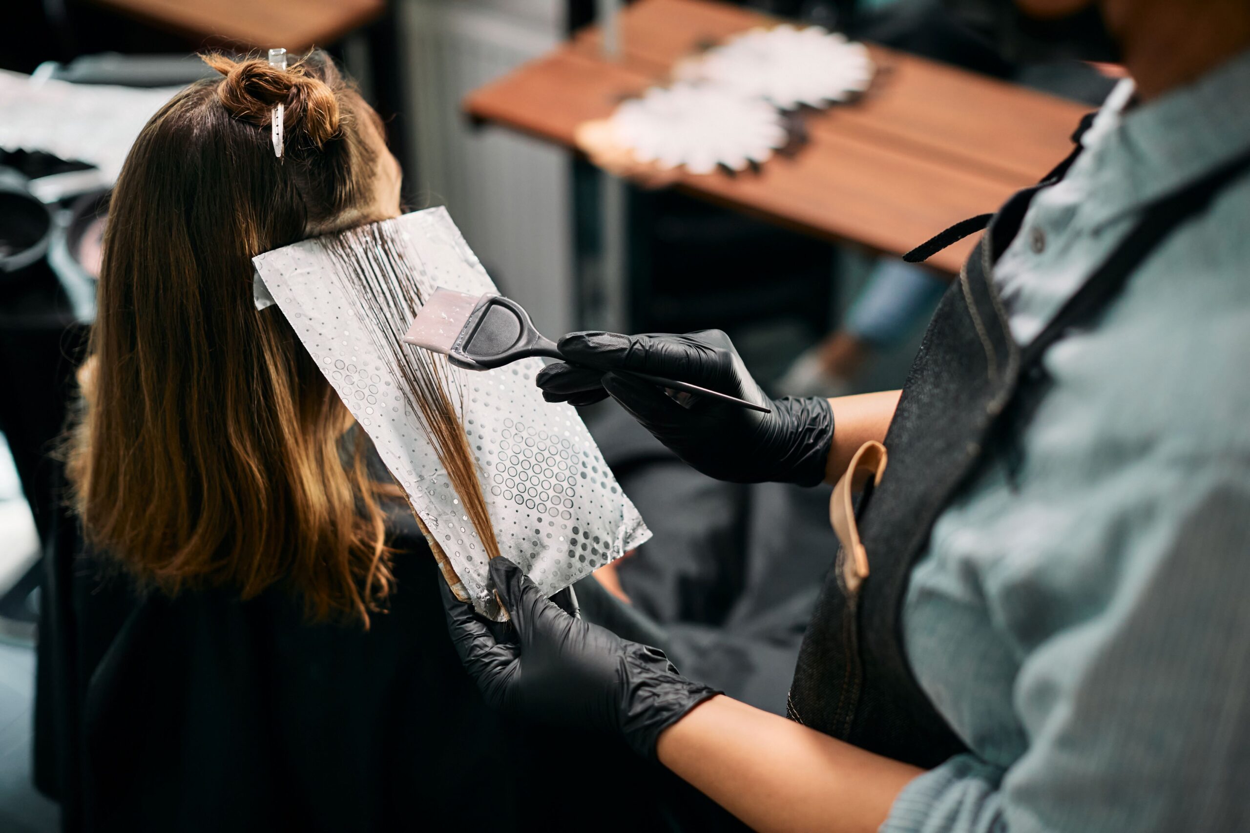 Ein Friseur trägt Farbe auf die Haare einer Frau auf.