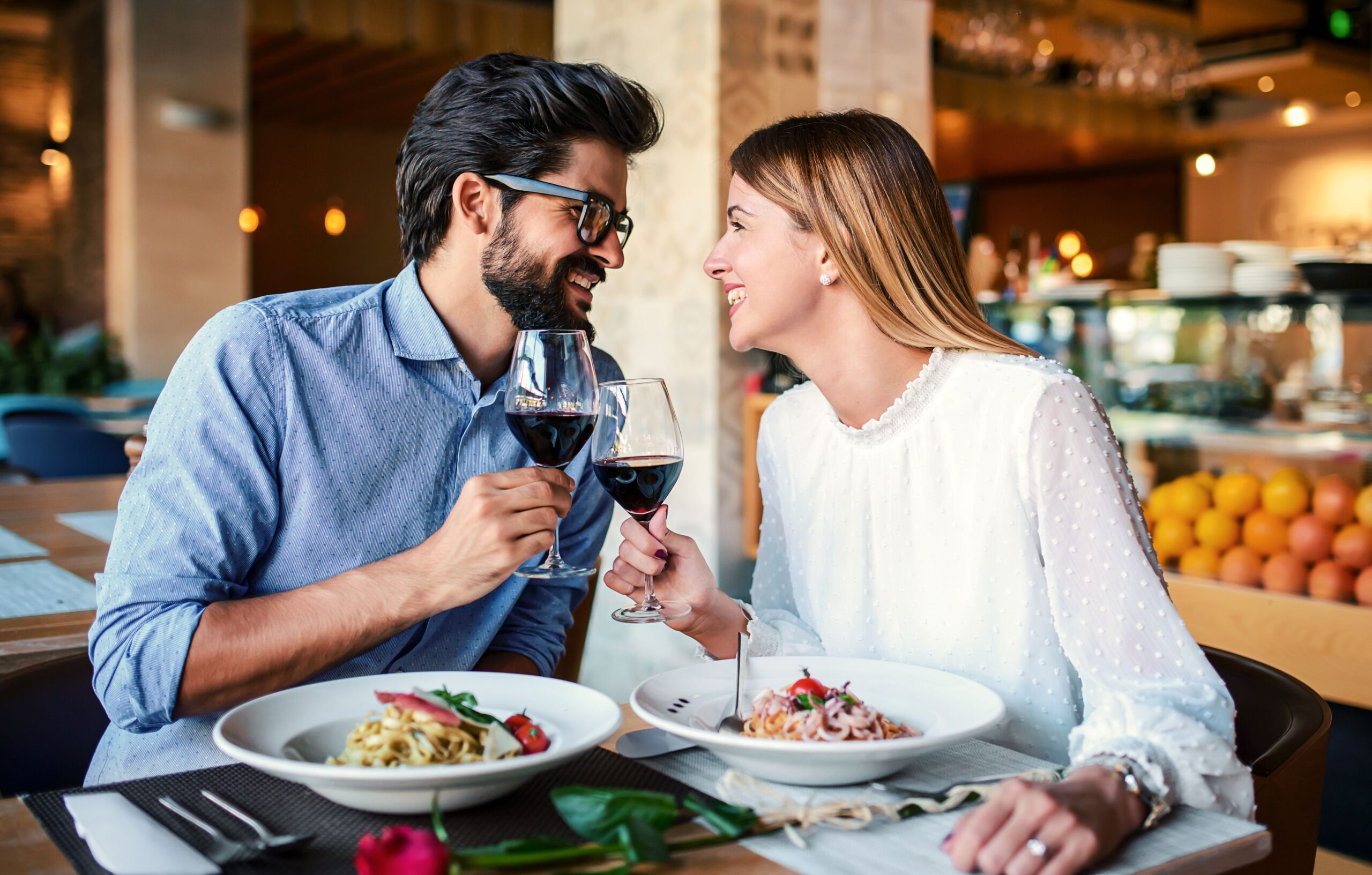 Ein Paar sitzt in einem Restaurant und stößt mit Rotwein an.