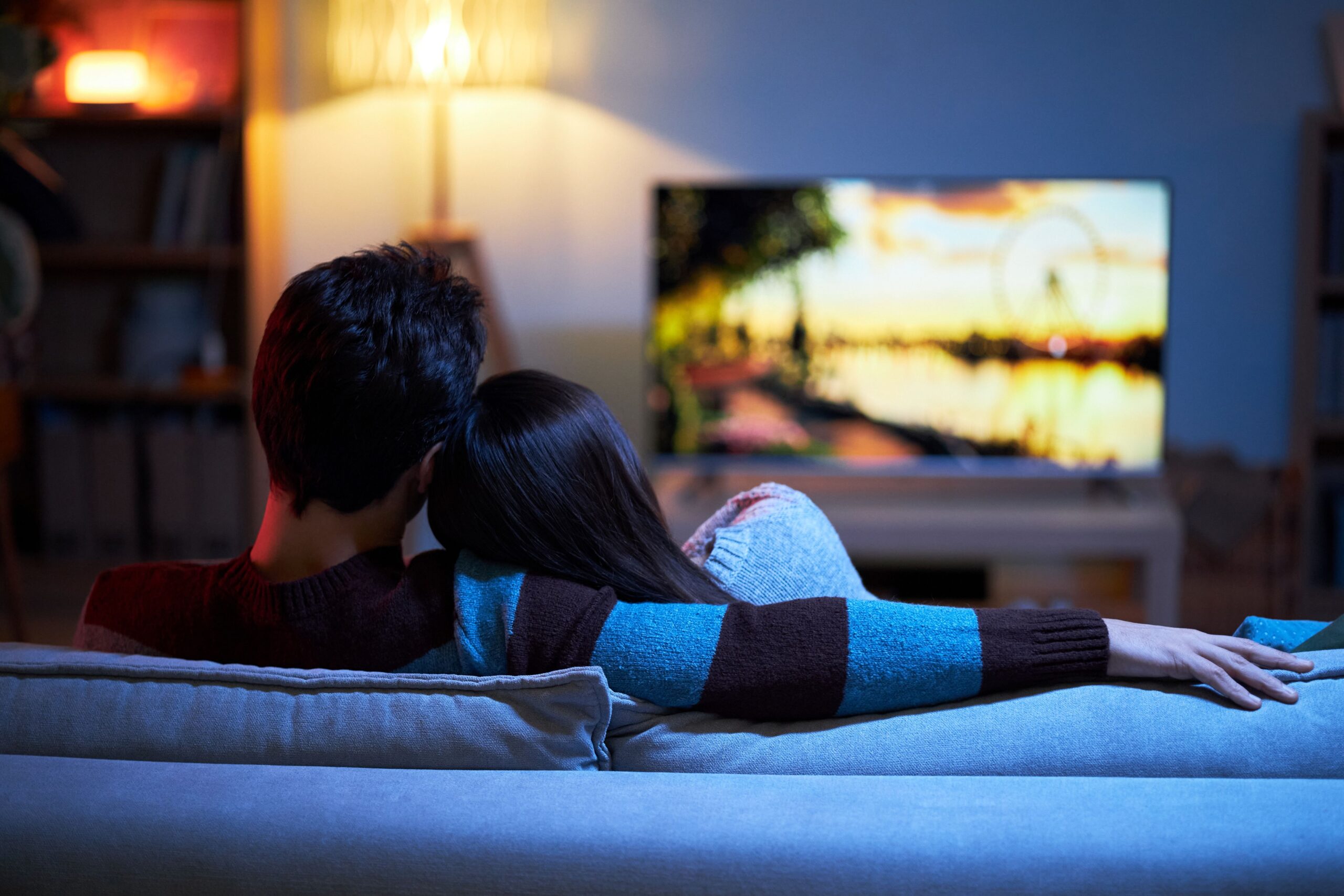 Ein Paar kuscheln auf dem Sofa und schaut einen Film.